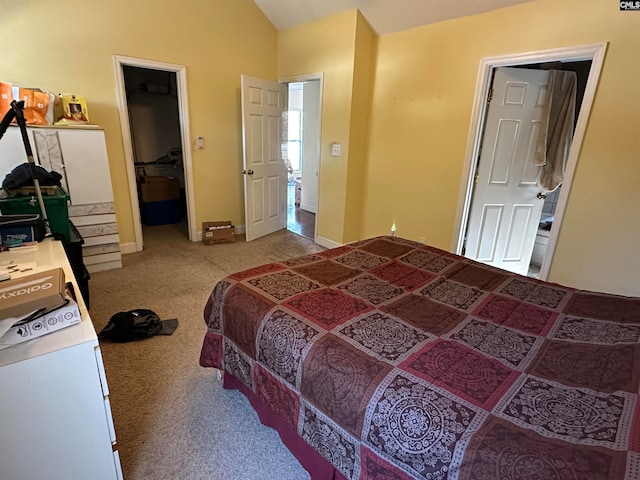 bedroom with vaulted ceiling, carpet floors, a closet, a walk in closet, and ensuite bath