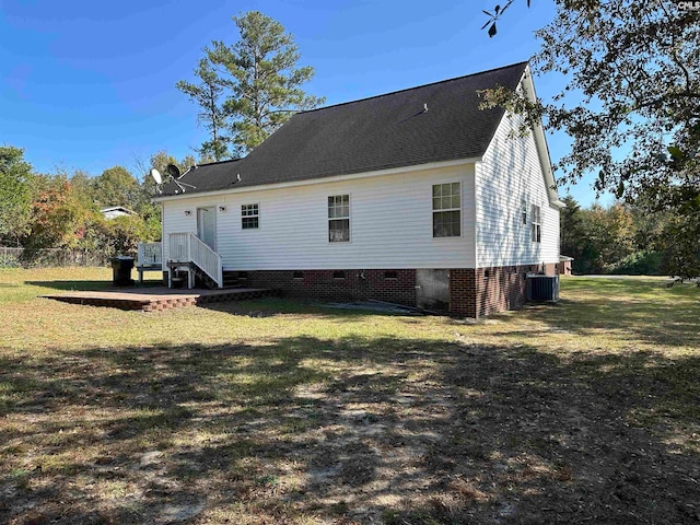 rear view of property with central air condition unit and a lawn