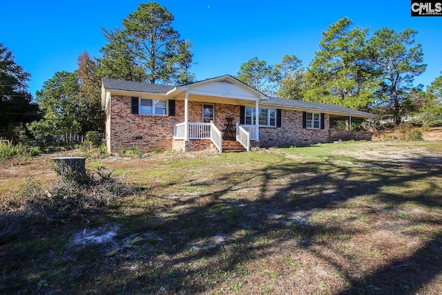 ranch-style house featuring covered porch and a front lawn