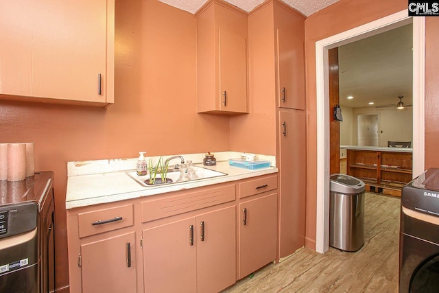 bathroom featuring hardwood / wood-style floors, sink, ceiling fan, a textured ceiling, and washer / dryer