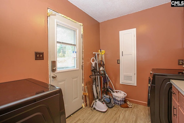 washroom featuring cabinets, washing machine and dryer, a textured ceiling, and light hardwood / wood-style flooring