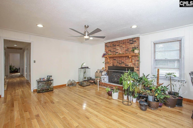 living room featuring hardwood / wood-style flooring, ceiling fan, crown molding, and a textured ceiling