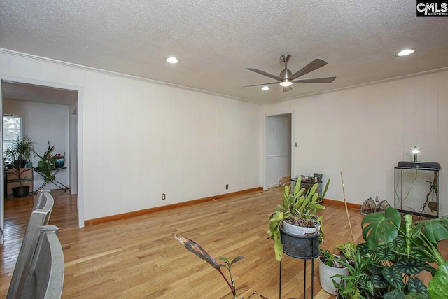 interior space featuring ceiling fan, light hardwood / wood-style floors, a textured ceiling, and ornamental molding