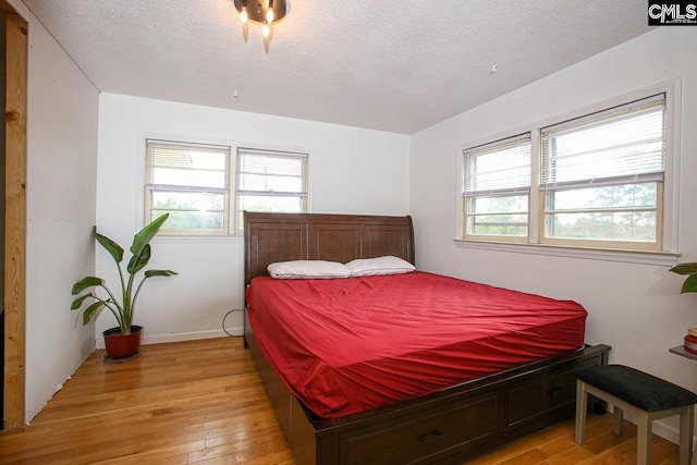 bedroom with a textured ceiling, multiple windows, and light hardwood / wood-style flooring