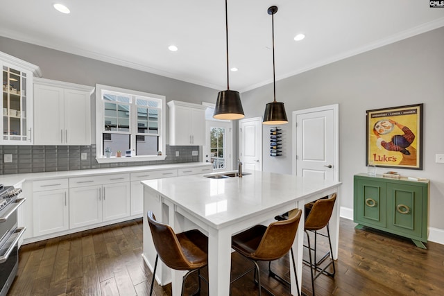 kitchen with white cabinets, a kitchen island with sink, dark wood-type flooring, and hanging light fixtures