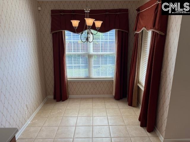 unfurnished dining area with an inviting chandelier and light tile patterned floors