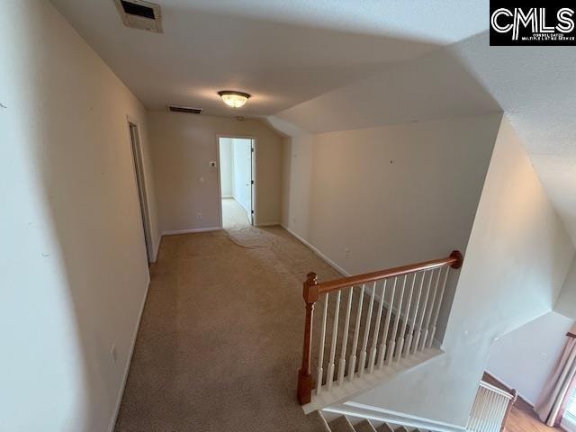 hallway with lofted ceiling and light carpet