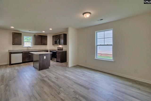 kitchen featuring sink, light hardwood / wood-style flooring, appliances with stainless steel finishes, a kitchen island, and dark brown cabinetry