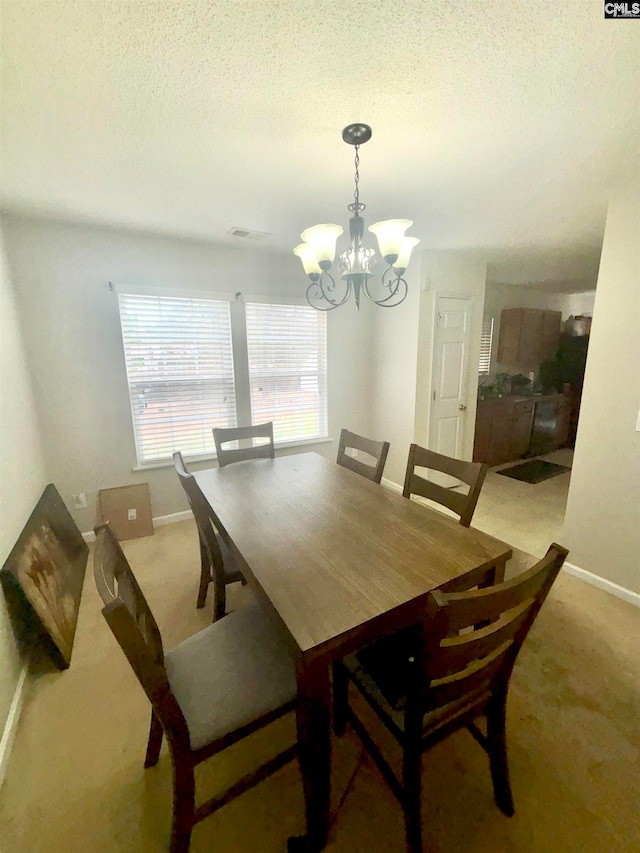 carpeted dining room featuring visible vents, baseboards, a chandelier, and a textured ceiling