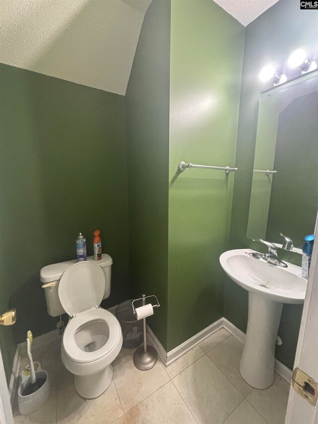 bathroom featuring tile patterned flooring, toilet, lofted ceiling, and baseboards