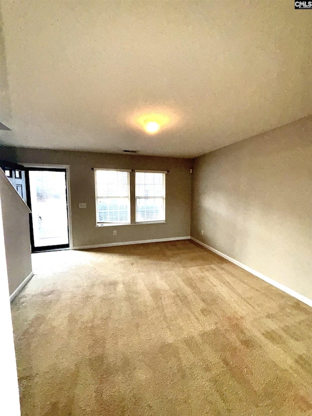 unfurnished room featuring baseboards, carpet floors, a textured ceiling, and visible vents