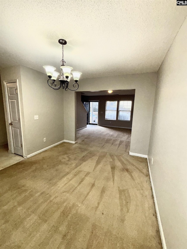 interior space featuring a chandelier, a textured ceiling, carpet, and baseboards