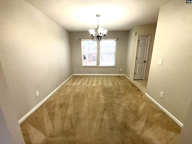 unfurnished dining area with a notable chandelier, carpet flooring, a textured ceiling, and baseboards