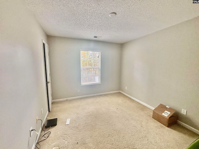 unfurnished room featuring visible vents, baseboards, light colored carpet, and a textured ceiling