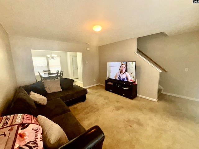 carpeted living room featuring baseboards, a notable chandelier, and stairs