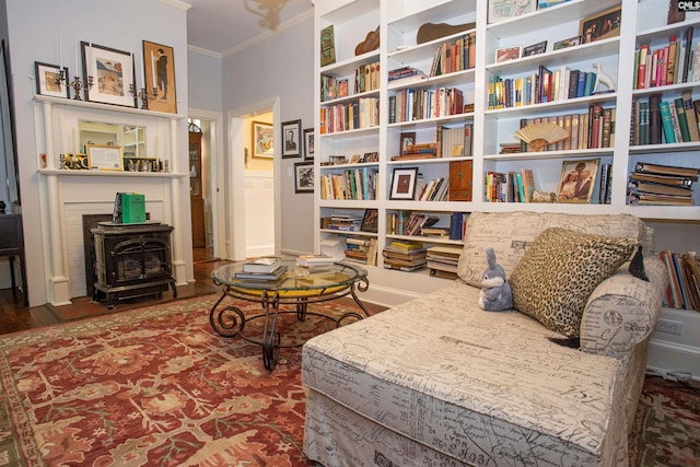 sitting room featuring a wood stove, ornamental molding, and wood-type flooring