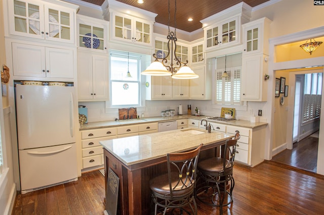 kitchen featuring dark wood-type flooring, an island with sink, sink, white cabinetry, and white appliances