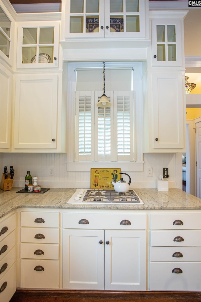 kitchen with white gas cooktop, light stone countertops, pendant lighting, white cabinetry, and tasteful backsplash