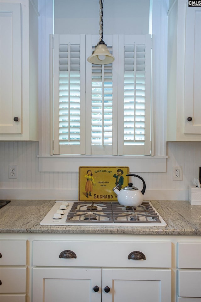 kitchen featuring light stone countertops, white gas cooktop, white cabinetry, and pendant lighting