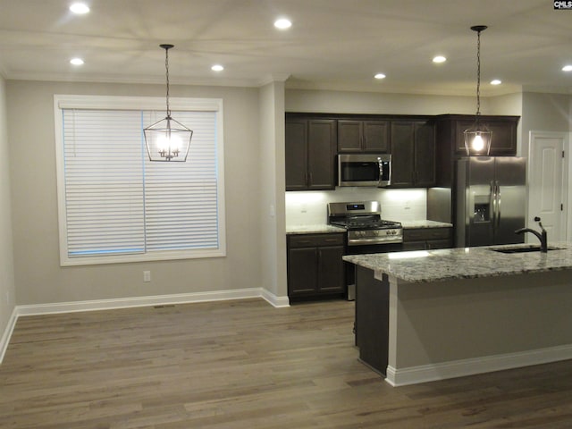 kitchen featuring pendant lighting, light stone countertops, sink, and stainless steel appliances