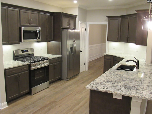 kitchen with sink, stainless steel appliances, crown molding, pendant lighting, and light hardwood / wood-style floors