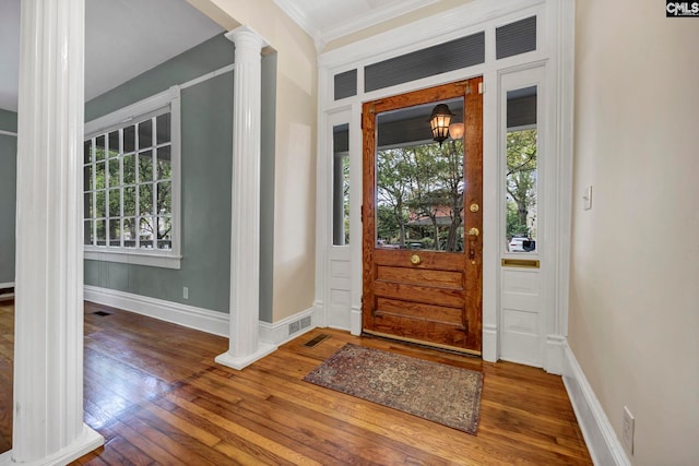 foyer with ornamental molding, hardwood / wood-style floors, and decorative columns