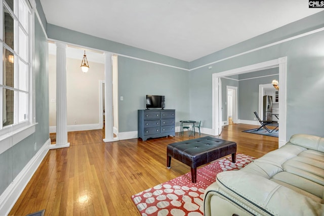 living room with light hardwood / wood-style flooring and ornate columns