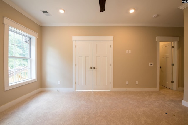 unfurnished bedroom with ornamental molding, light colored carpet, a closet, and ceiling fan