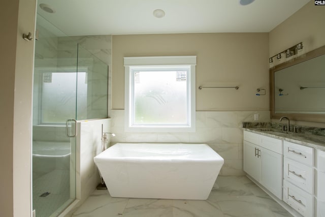 bathroom featuring vanity, independent shower and bath, and tile walls