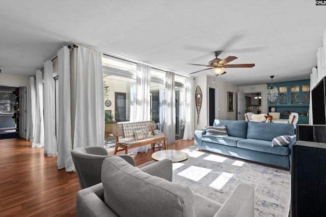 living room featuring dark wood-type flooring and ceiling fan with notable chandelier