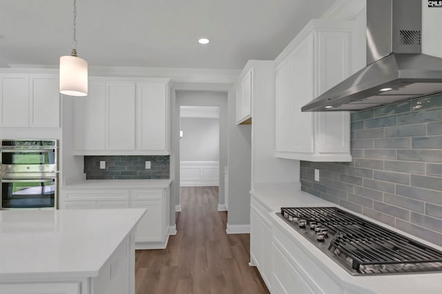 kitchen with white cabinetry, tasteful backsplash, wall chimney range hood, and appliances with stainless steel finishes