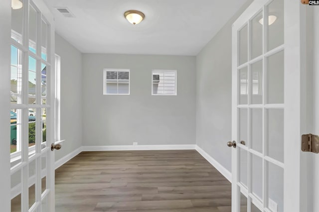 spare room with french doors, a healthy amount of sunlight, and wood-type flooring