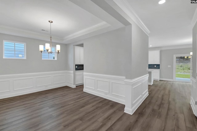 unfurnished dining area featuring a notable chandelier, ornamental molding, a fireplace, and dark hardwood / wood-style floors