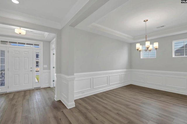 foyer entrance featuring dark wood-type flooring, crown molding, a tray ceiling, and plenty of natural light