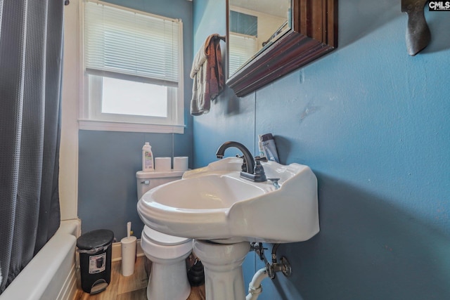 bathroom with toilet, hardwood / wood-style flooring, and shower / bathtub combination with curtain