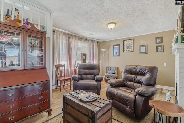 living room featuring light hardwood / wood-style flooring, a textured ceiling, a fireplace, and crown molding