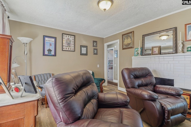 living room featuring crown molding, a fireplace, a textured ceiling, and light hardwood / wood-style floors