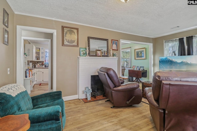 living room with ornamental molding, a fireplace, a textured ceiling, and light wood-type flooring