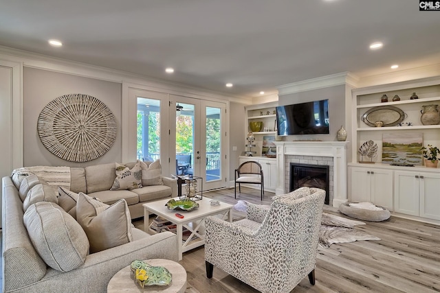 living room with built in features, ornamental molding, light hardwood / wood-style flooring, and a brick fireplace