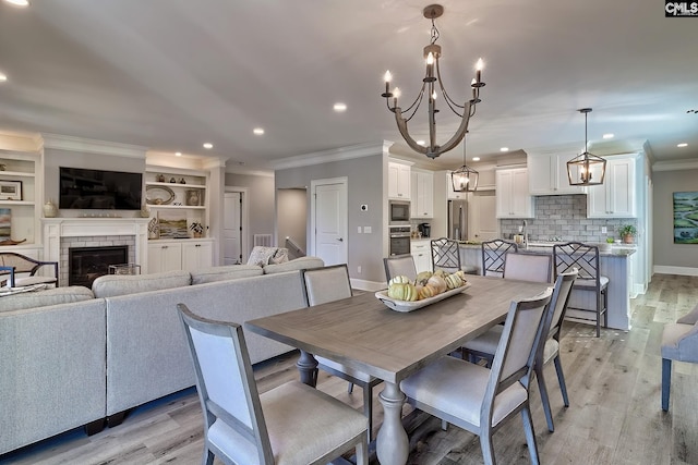 dining room with light hardwood / wood-style floors, ornamental molding, and a brick fireplace