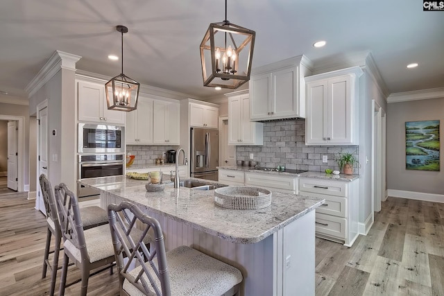 kitchen featuring white cabinets, tasteful backsplash, a kitchen island with sink, pendant lighting, and stainless steel appliances