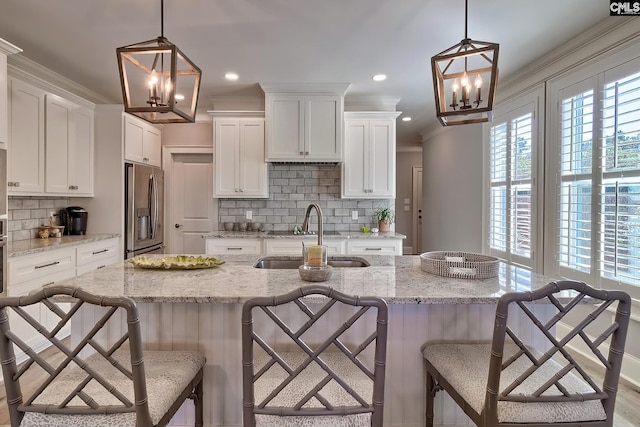 kitchen featuring ornamental molding, sink, stainless steel fridge with ice dispenser, and pendant lighting