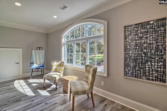 living area featuring crown molding and light hardwood / wood-style floors