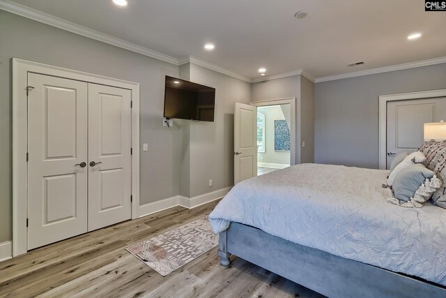 bedroom with a closet, light hardwood / wood-style floors, crown molding, and ensuite bathroom