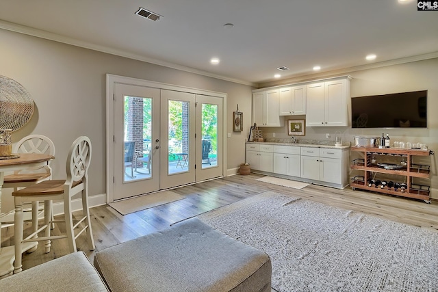 interior space featuring french doors, light hardwood / wood-style flooring, ornamental molding, sink, and white cabinetry