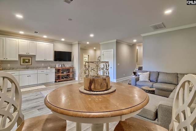 interior space with sink, crown molding, and light hardwood / wood-style flooring