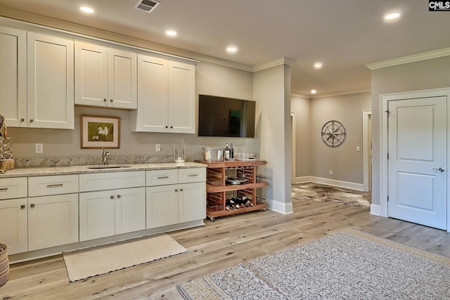 kitchen featuring ornamental molding, sink, and light wood-type flooring