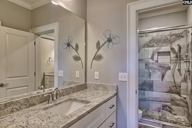 bathroom with vanity, ornamental molding, toilet, and a tile shower