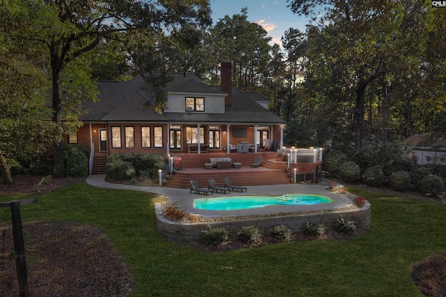 back house at dusk with a wooden deck, a yard, and a patio