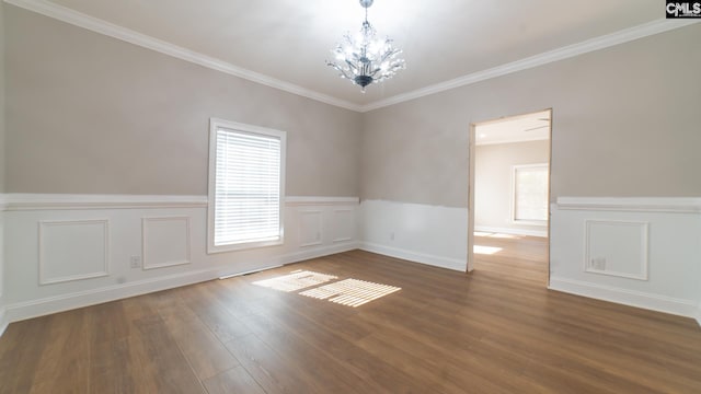 empty room featuring dark hardwood / wood-style flooring, an inviting chandelier, and crown molding